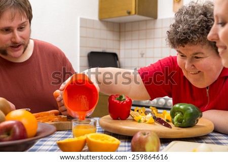 a mentally disabled woman and two caretakers cooking together Royalty-Free Stock Photo #259864616