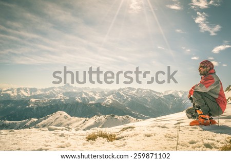 Alpinist on the mountain summit. Shot in backlight, stunning panoramic view of the alpine arc. Concept of success and conquering the top. Toned image, old retro touch. Royalty-Free Stock Photo #259871102