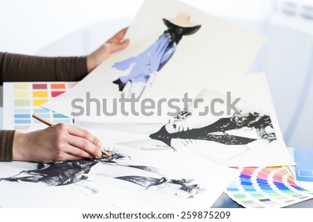 Extreme close up of fashion designer at work with fashion sketches and color charts.