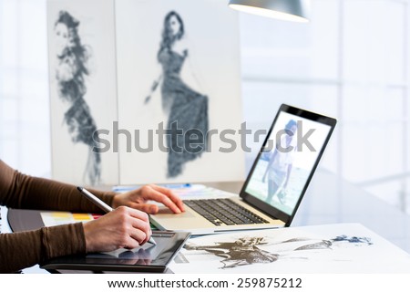 Extreme close up of fashion student designing new collection with digital tablet and laptop.