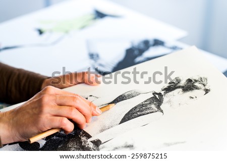 Extreme close up of female fashion designers hand creating fashion sketch.