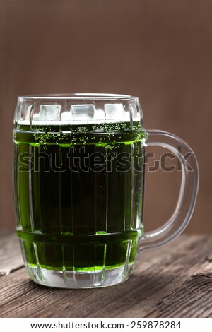 Glass of green beer on vintage wooden background
