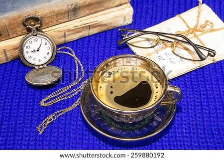 Coffee, pictures, watches, glasses and old tattered books on a blue knitted background.