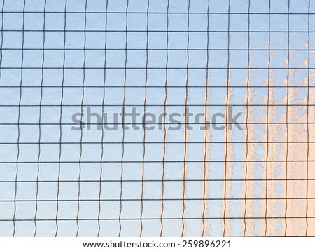 Wall of textured translucent glass with metal mesh