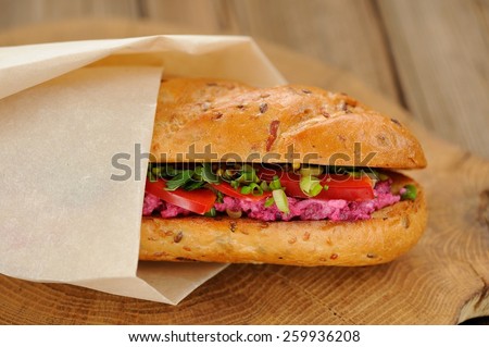Sandwich with beetroot, bell pepper and scallion wrapped in paper