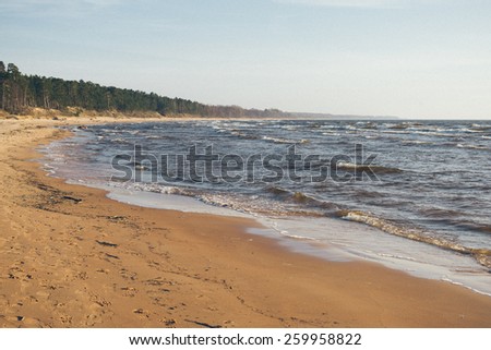 Shoreline of Baltic sea beach with rocks and sand dunes under clouds - grainy retro vintage film effect