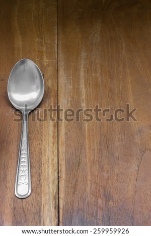 Stainless spoon on dark wooden table.