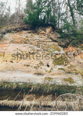 sandstone cliffs on the river shore in the Gaujas National Park, Latvia - grainy retro vintage film effect