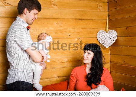 Young beautiful family of 3 persons Mum, Dad and little daughter posing in the studio