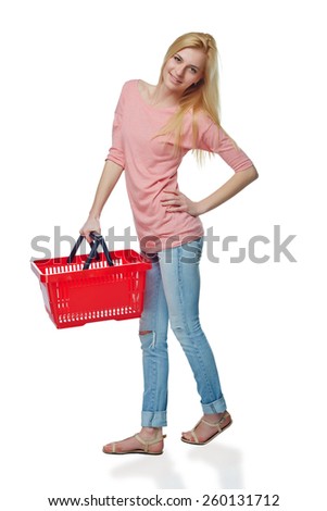 Shopping woman. Full length of surprised casual young woman standing smiling with empty shopping cart basket looking out of frame, over white background