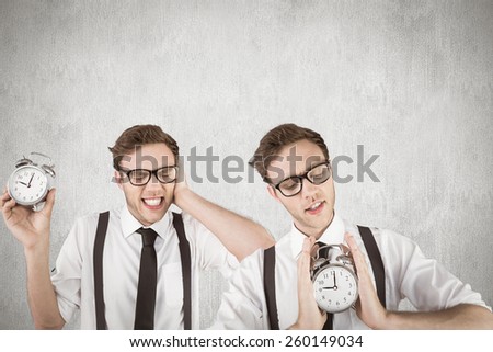 Nerdy businessman with alarm clock against white and grey background