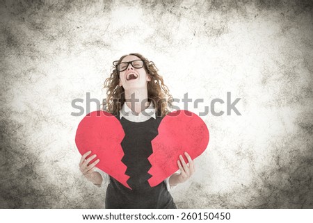 Geeky hipster holding a broken heart card against grey background