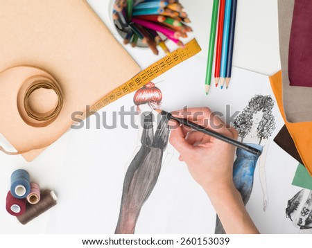 female hand drawing fashion sketch on desk with designing equipment