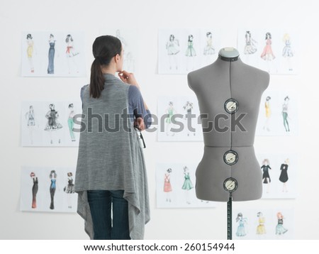 successful female fashion designer looking at drawings in her studio