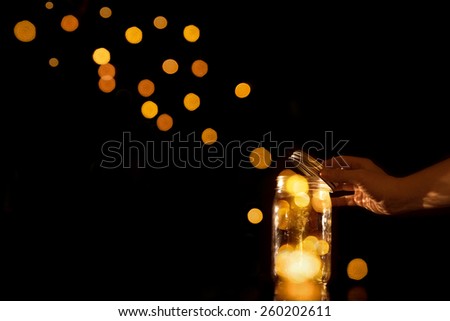 Clear transparent jar jug glass container with magical balls dots bits of bokeh light leaving escaping flying away or being released let go free from confinement capture isolated on black background Royalty-Free Stock Photo #260202611