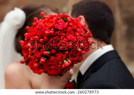 wedding couple covering his face with bouquet of flowers.