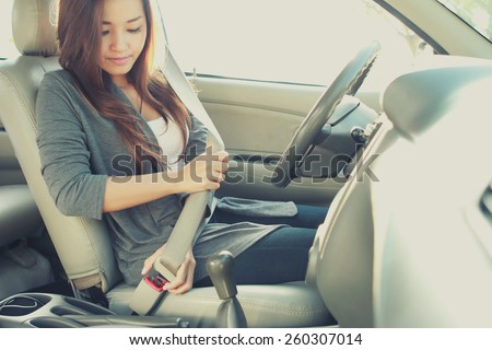 portrait of young woman putting on a seatbelt for safety Royalty-Free Stock Photo #260307014