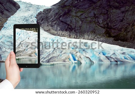 travel concept - tourist taking photo of briksdal glacier in Norway on mobile gadget
