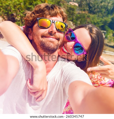 Happy lovers, woman and man traveling on vacation travel in tropical island enjoying romance.  Attractive couple  making selfie, smiling and have fun together. Instagram filter.