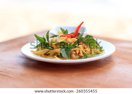 Natural light photo with shallow DOF of spicy green mango salad on a wooden table