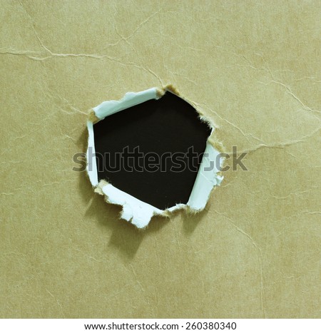 Hole ripped in paper on black background. Copy space
