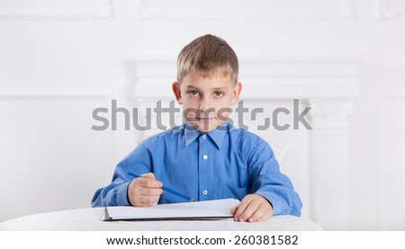  caucasian boy draws a pencil on the album 
