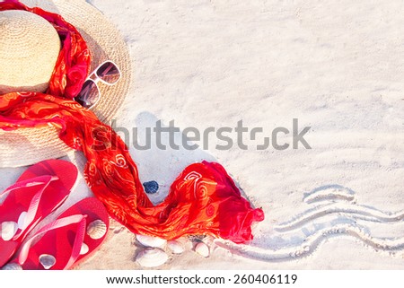 Sand texture (background) with flip flop sandals, hat, pareos (sarong), sunglasses, shellfishes (scallop) on the beach. The empty pattern for message. Summer vacations (travel) concept. Copy space.