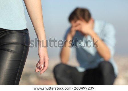Breakup of a couple with a sad man in the background and the girlfriend leaving him in the foreground Royalty-Free Stock Photo #260499239