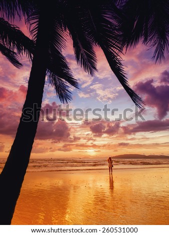 Woman taking pictures of the sunset on the beach of Ao Nang in Krabi Thailand.