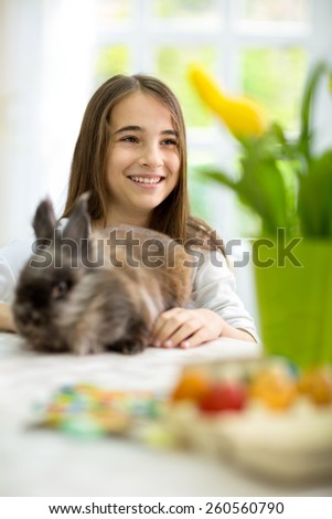 Cute smiling girl siting  for the Easter table with bunny