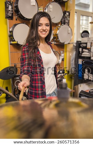 Young attractive girl is playing the drums in the music store.