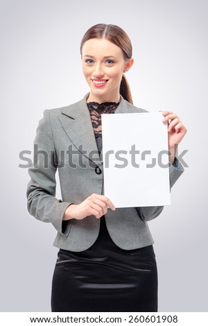 Beautiful young business woman in formal wear holding blank card. Isolated on grey background smiling female portrait.