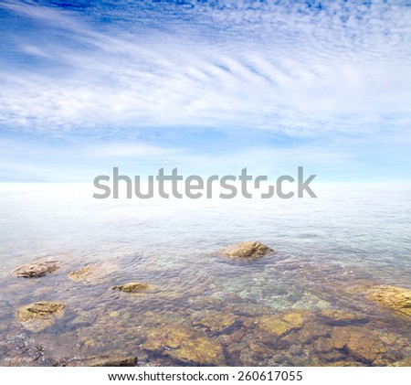 rocky sea shallows on a background of blue sky with clouds