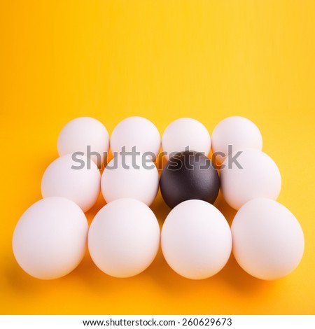 business concept background with a black egg surrounded by normal eggs