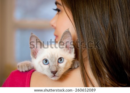 Gorgeous young brunette holding sweet young siamese kitten.