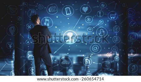 Businessman drawing social media connection scheme on glass window with night cityscape background 