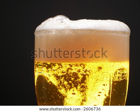 Beer within mug with foam over black background
