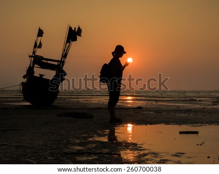Silhouette of a girl and fishing boat  in sunset on the beach