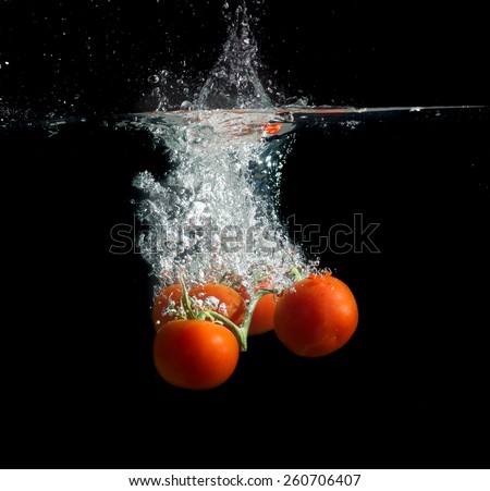 Tomatoes in the water with air bubbles on a black background