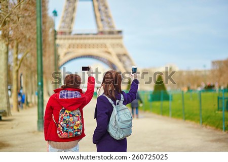 Two young tourists in Paris taking picture of the Eiffel tower