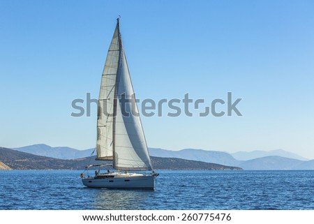 Yacht is moving along the coast. Sailing yacht in blue sea. 