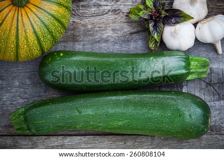 Fresh green zuchinni, squash with basil leaves and garlic on wooden board, top view