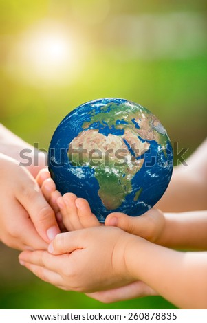 People holding 3d planet in hands against green spring background. Earth day holiday concept. Elements of this image furnished by NASA