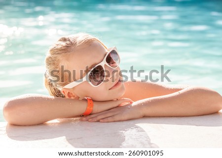 Beautiful little blond girl with sunglasses in outdoor pool, close-up summer portrait, vintage toned photo, old style filter effect