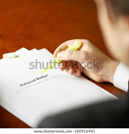 Balanced budget definition as a shallow depth of field close-up composition of a man in a business suit working with the text