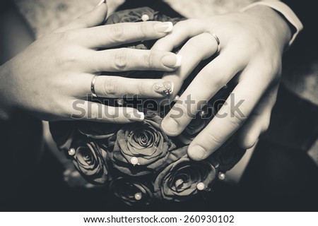 Hands newlyweds on a bouquet of roses