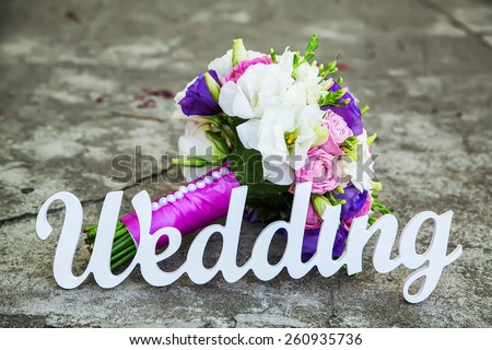 Word of wedding and bridal bouquet on the table on a stone