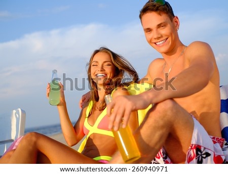 Young couple relaxing on a deck chairs on a beach 