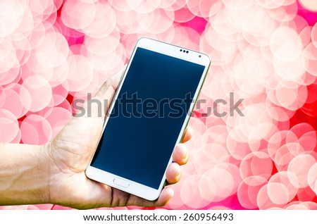 Man hand holding smartphone in bokeh background soft focus.