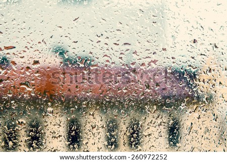 Rainy background with flowing down water drops on window glass, vintage toned photo with instagram style tonal filter effect 